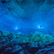 Divers in the illuminated submerged cave.